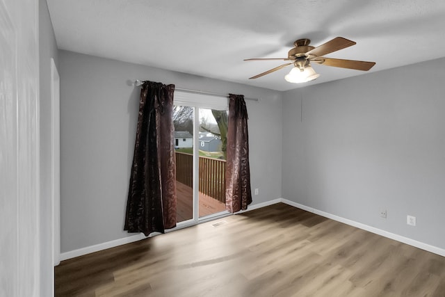 unfurnished room with ceiling fan, visible vents, baseboards, and wood finished floors