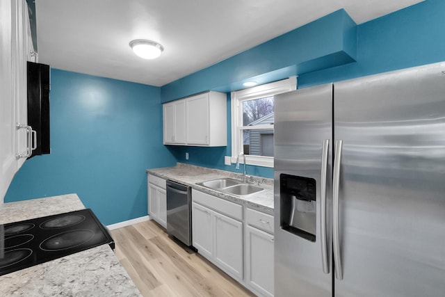 kitchen featuring light countertops, white cabinets, appliances with stainless steel finishes, light wood finished floors, and a sink