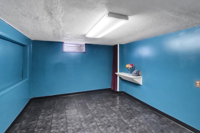 empty room featuring baseboards, dark floors, and a textured ceiling
