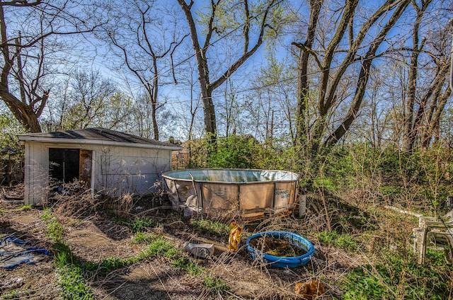 view of yard featuring an outdoor structure, an outdoor pool, and a storage unit