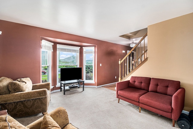 carpeted living room with stairway and baseboards