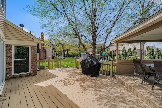 wooden terrace featuring a playground and a grill