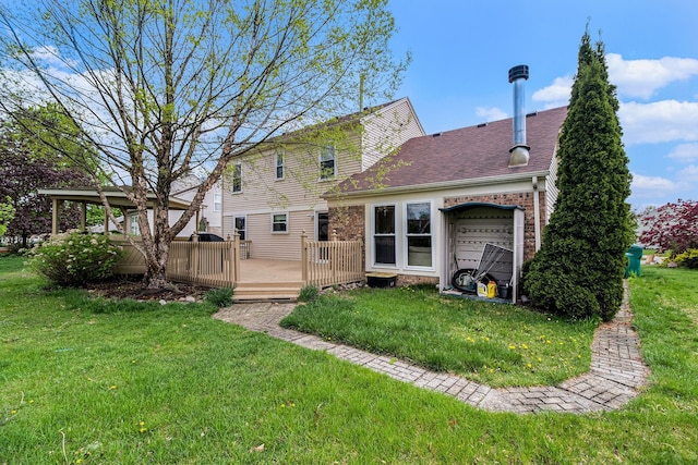 back of property with a yard, a wooden deck, roof with shingles, and brick siding