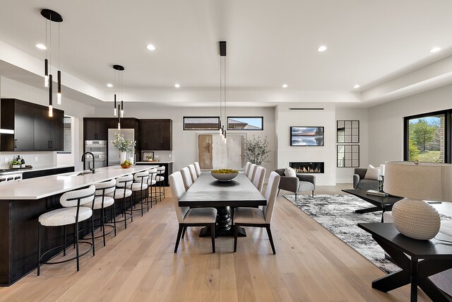 49351 Villa Dr, Novi, MI 48374 - dining space featuring a tray ceiling, recessed lighting, a glass covered fireplace, and light wood-type flooring