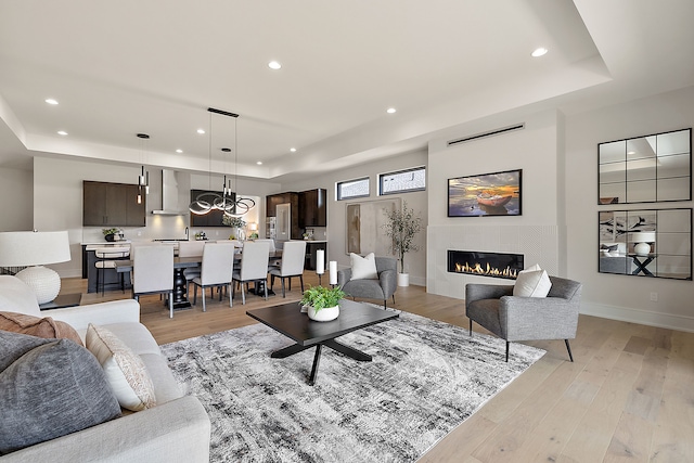49351 Villa Dr, Novi, MI 48374 - living room featuring a raised ceiling, recessed lighting, light wood-style floors, a glass covered fireplace, and baseboards