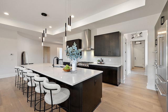 49351 Villa Dr, Novi, MI 48374 - kitchen with wall chimney range hood, a sink, light wood-style flooring, a raised ceiling, and recessed lighting