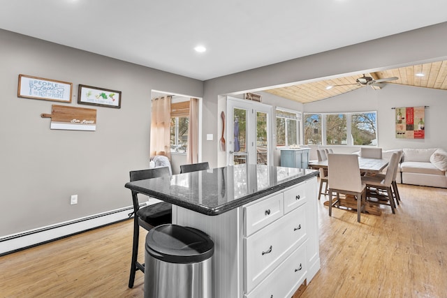 kitchen featuring light wood-style flooring, white cabinets, lofted ceiling, and plenty of natural light