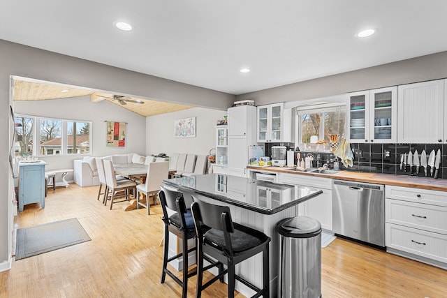 kitchen featuring butcher block countertops, a sink, white cabinetry, dishwasher, and vaulted ceiling with beams