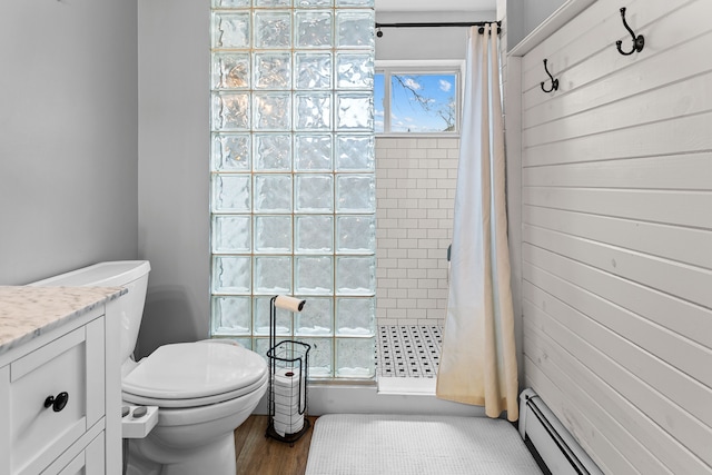 bathroom with vanity, baseboard heating, a stall shower, toilet, and wood finished floors