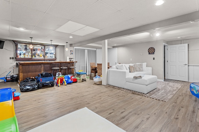 living area with a paneled ceiling, a dry bar, wood finished floors, and recessed lighting