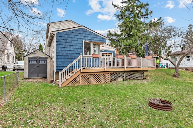 rear view of house with a fire pit, a shed, fence, an outbuilding, and a wooden deck