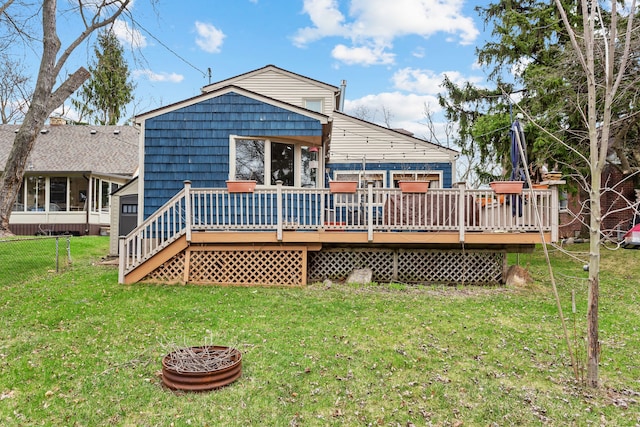 rear view of house featuring a wooden deck, fence, and a lawn