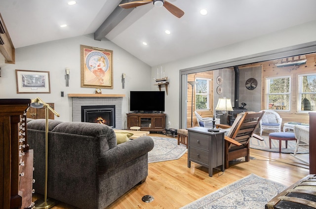living area with a wealth of natural light, vaulted ceiling with beams, light wood-style flooring, and a ceiling fan