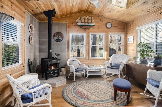 sitting room featuring a wood stove, wood ceiling, wood finished floors, and lofted ceiling