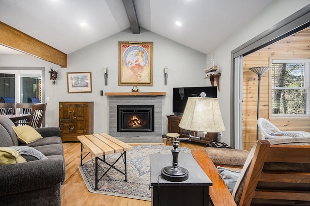 living room featuring a fireplace, light wood-type flooring, and vaulted ceiling with beams