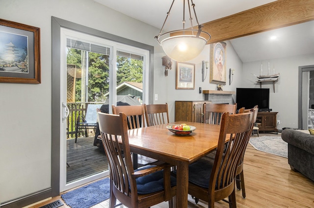dining room featuring light wood-type flooring and lofted ceiling with beams