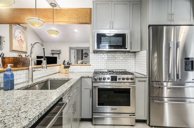 kitchen with backsplash, gray cabinetry, light stone countertops, appliances with stainless steel finishes, and a sink