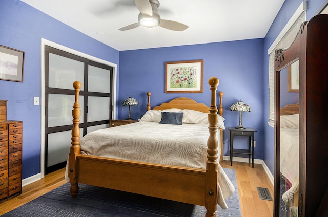 bedroom featuring visible vents, baseboards, ceiling fan, and wood finished floors