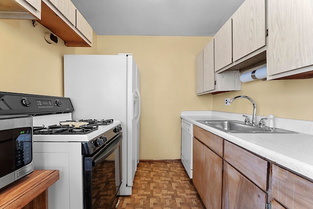 kitchen with gas range, white dishwasher, a sink, light countertops, and stainless steel microwave