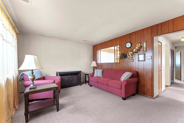 living room with visible vents, carpet, and wood walls