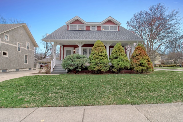 bungalow with a front lawn, a shingled roof, and covered porch