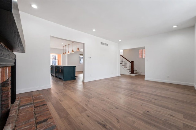 1459 Edison St, Detroit, MI 48206 - unfurnished living room with visible vents, a brick fireplace, recessed lighting, wood finished floors, and stairs