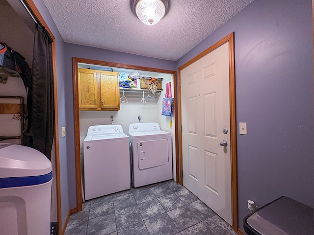 laundry room featuring washing machine and dryer, cabinet space, and a textured ceiling