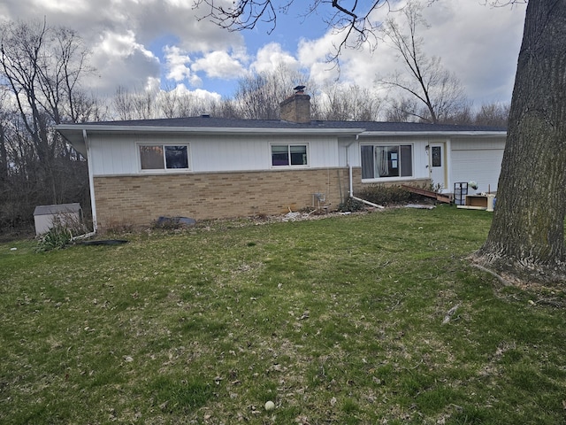 view of front of property with a front yard, brick siding, and a chimney