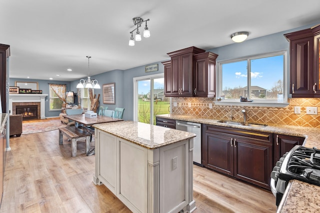 316 Lenox Ln, Brighton, MI 48114 - kitchen with dishwasher, a sink, a wealth of natural light, black gas range oven, and a glass covered fireplace