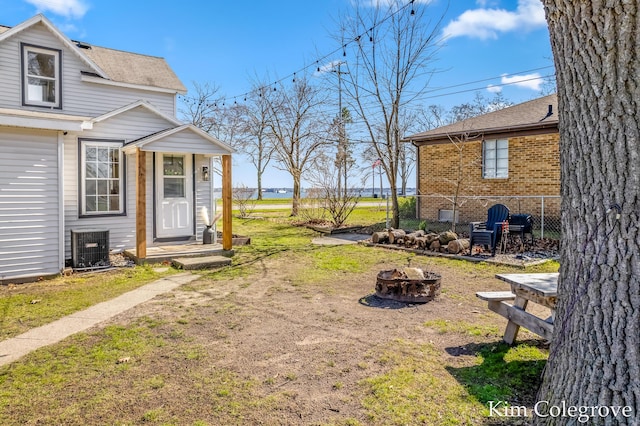 view of yard featuring central AC unit, fence, and a fire pit