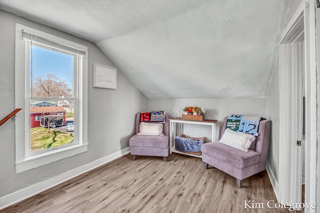 sitting room featuring baseboards, lofted ceiling, wood finished floors, and a textured ceiling