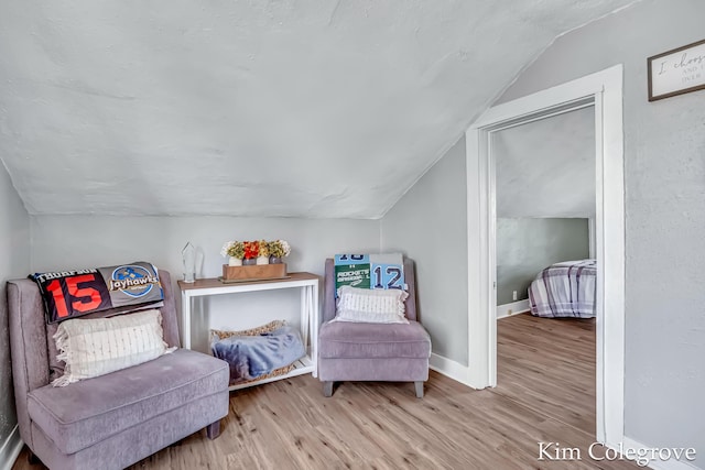 sitting room featuring baseboards, vaulted ceiling, and wood finished floors
