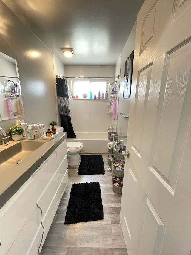 full bath featuring toilet, vanity, wood finished floors, and shower / bath combination with curtain