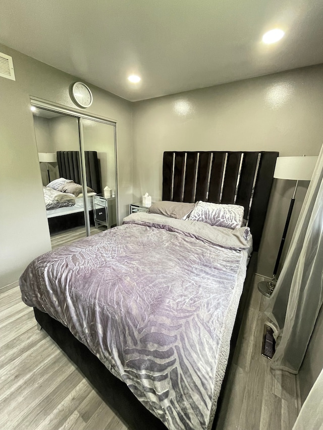 bedroom featuring wood finished floors, a closet, visible vents, and recessed lighting