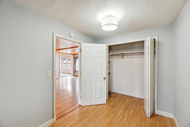 6308 E Becht Rd, Coloma, MI 49038 - unfurnished bedroom with light wood finished floors, a textured ceiling, a closet, and baseboards