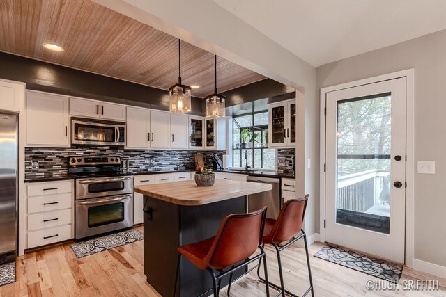 2376 Bob White Ct SE, Grand Rapids, MI 49546 - kitchen featuring tasteful backsplash, glass insert cabinets, white cabinetry, wooden counters, and stainless steel appliances