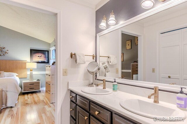 2376 Bob White Ct SE, Grand Rapids, MI 49546 - ensuite bathroom featuring a sink, double vanity, vaulted ceiling, and wood finished floors