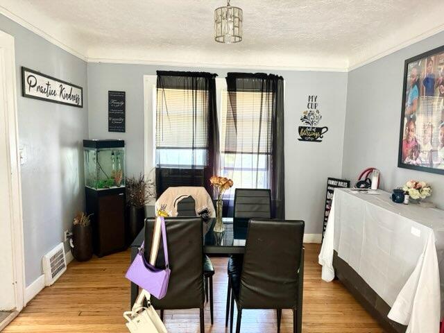 5793 Yorkshire Rd, Detroit, MI 48224 - dining area with baseboards, light wood finished floors, a textured ceiling, and ornamental molding