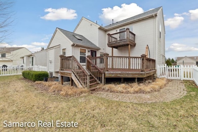 back of property with a yard, a balcony, a fenced backyard, and a deck