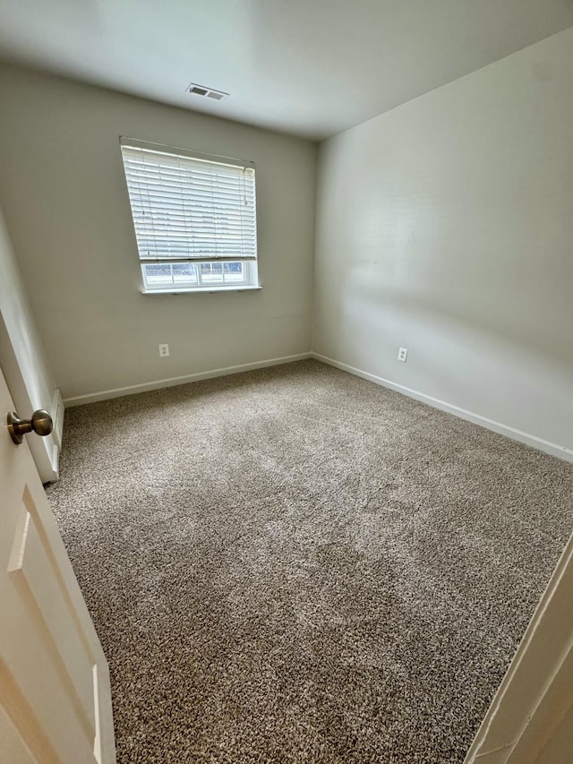 carpeted spare room with visible vents and baseboards