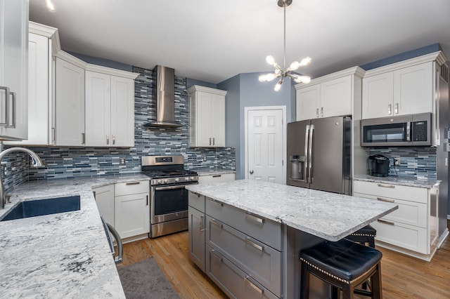 3885 Silver Charm Ln, Howell, MI 48843 - kitchen featuring appliances with stainless steel finishes, wall chimney range hood, a sink, backsplash, and wood finished floors