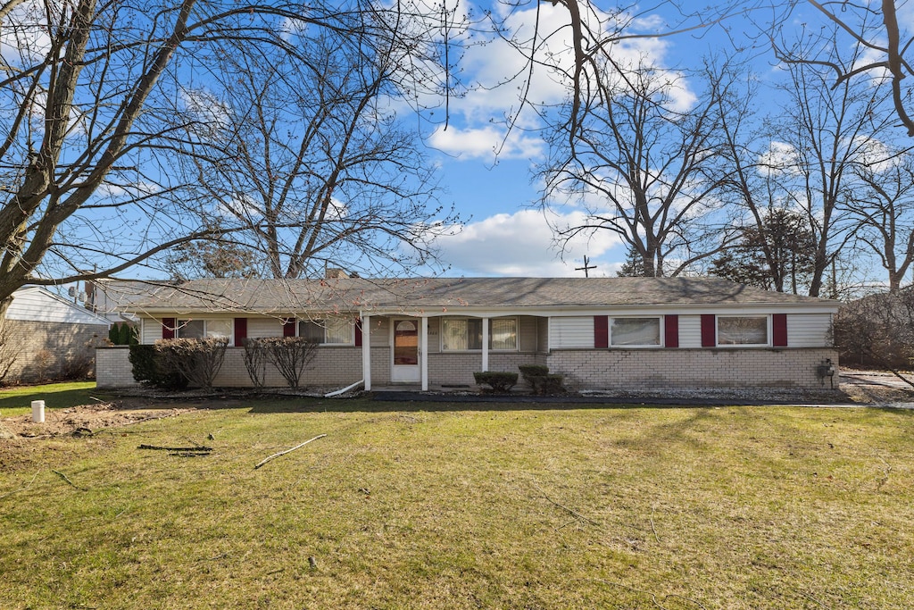 single story home featuring a chimney, a front lawn, and brick siding