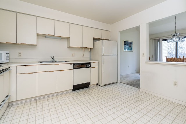 kitchen with white cabinets, light countertops, a sink, white appliances, and pendant lighting