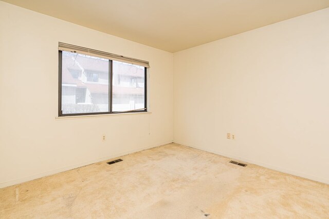 carpeted empty room featuring baseboards and visible vents