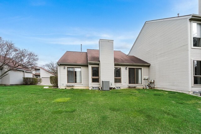 rear view of property featuring a chimney and a lawn