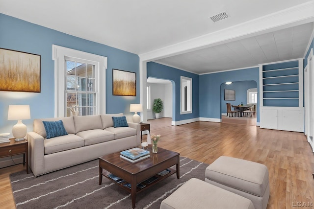 living area with arched walkways, wood finished floors, and visible vents