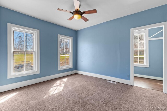 unfurnished room with carpet flooring, visible vents, baseboards, and a ceiling fan