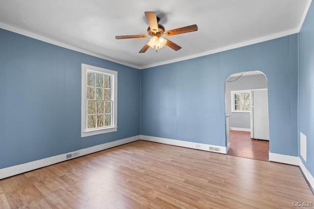 spare room with visible vents, ceiling fan, arched walkways, and wood finished floors