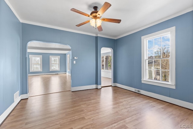 spare room featuring arched walkways, visible vents, crown molding, and wood finished floors