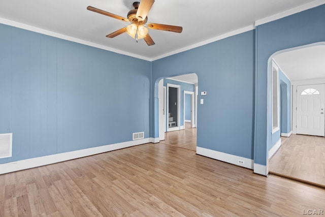 empty room with visible vents, a ceiling fan, arched walkways, and wood finished floors